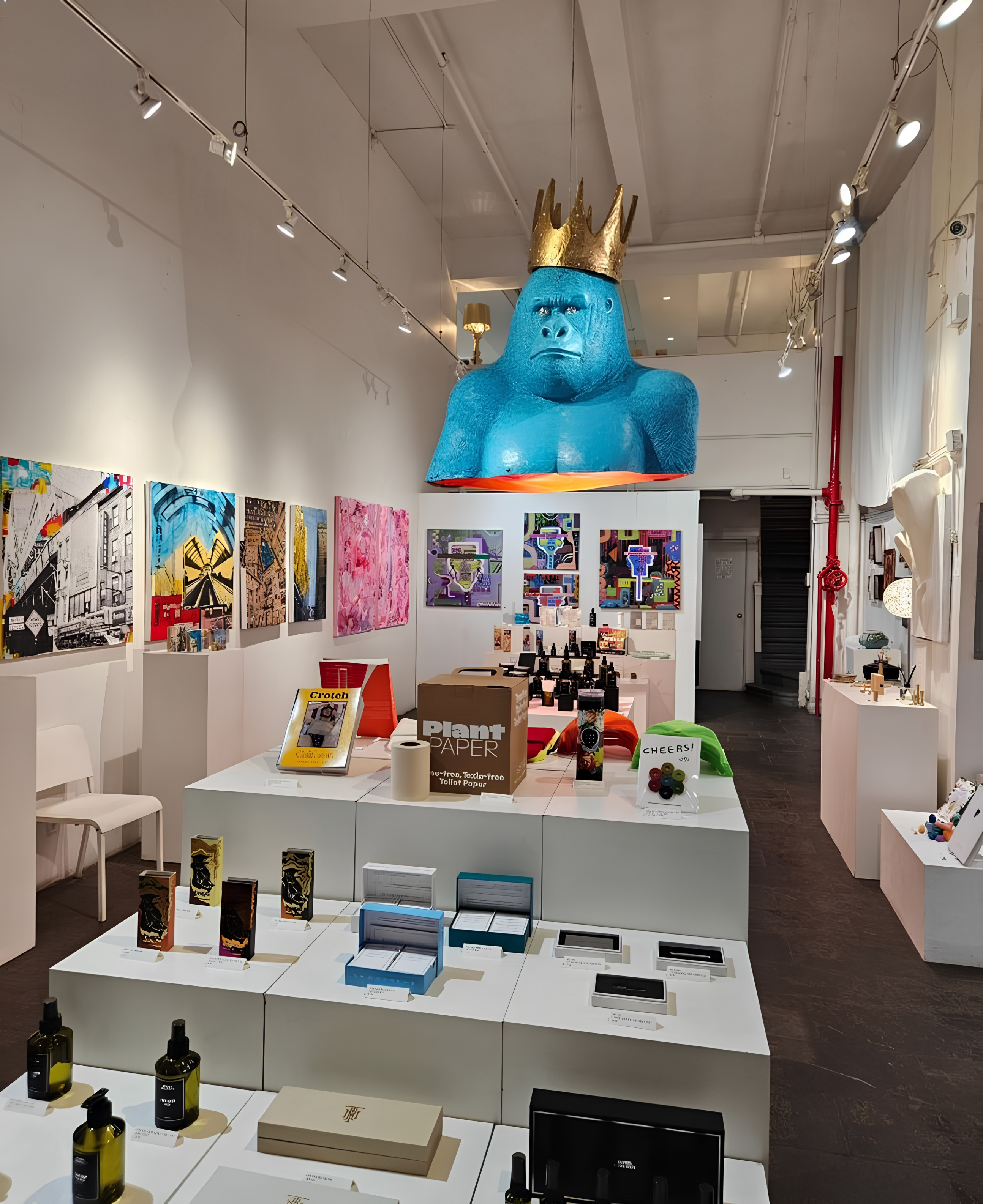Art gallery with a large blue gorilla sculpture wearing a crown on the ceiling.